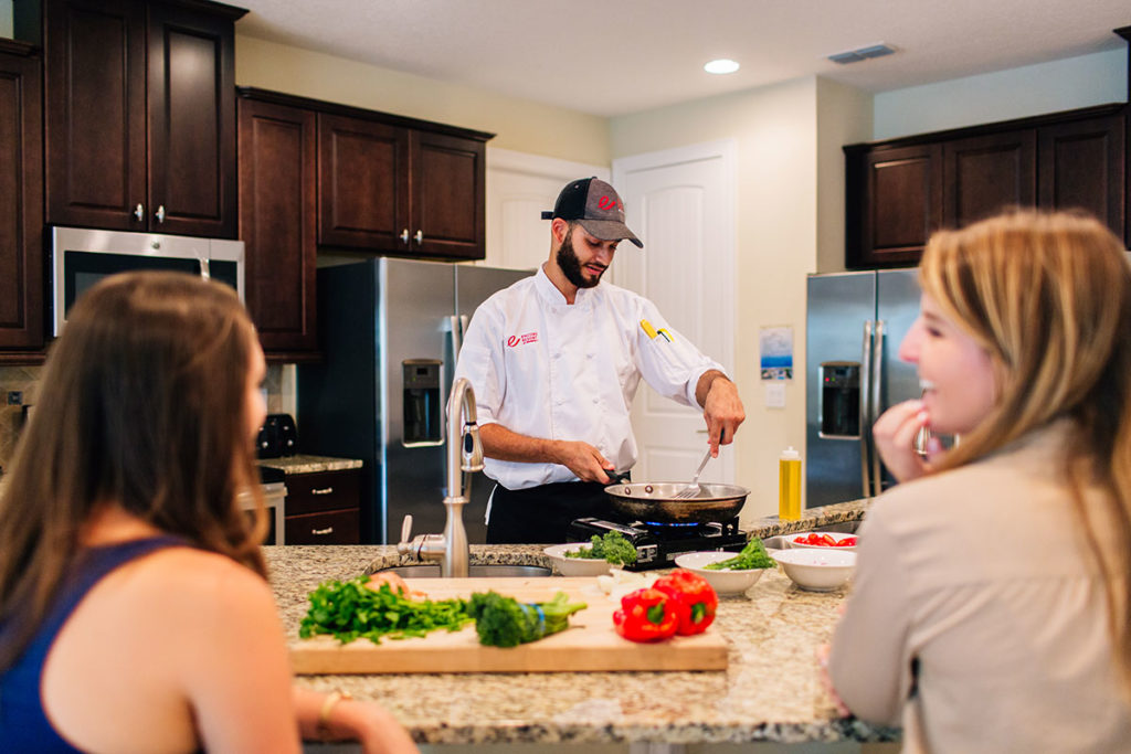 One of Encore’s expert chefs prepares a meal in front of guests at their vacation home rental.
