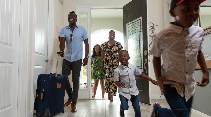 Family with young kids excitedly run into their vacation home as they arrive.