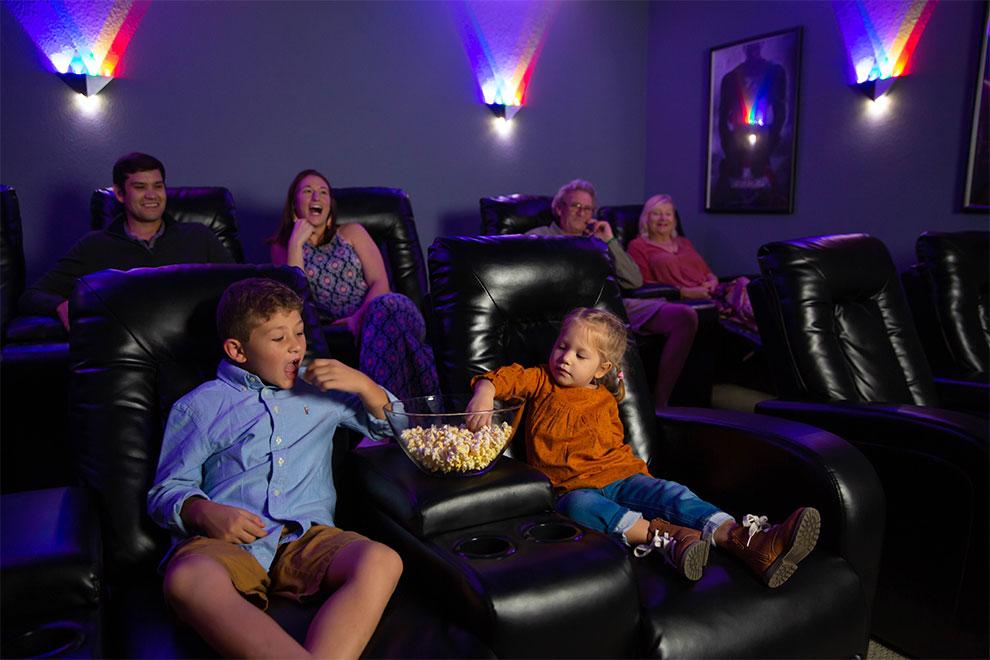 Family with kids eating popcorn while watching a movie in their vacation home theater.