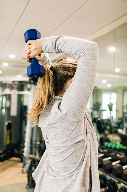 Woman lifting a hand weight during a workout at the Encore Resort Fitness Center.