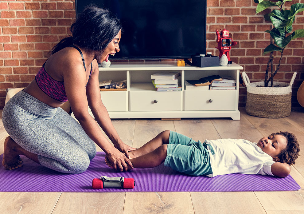 Mother and young son working out together on a yoga mat at home.
