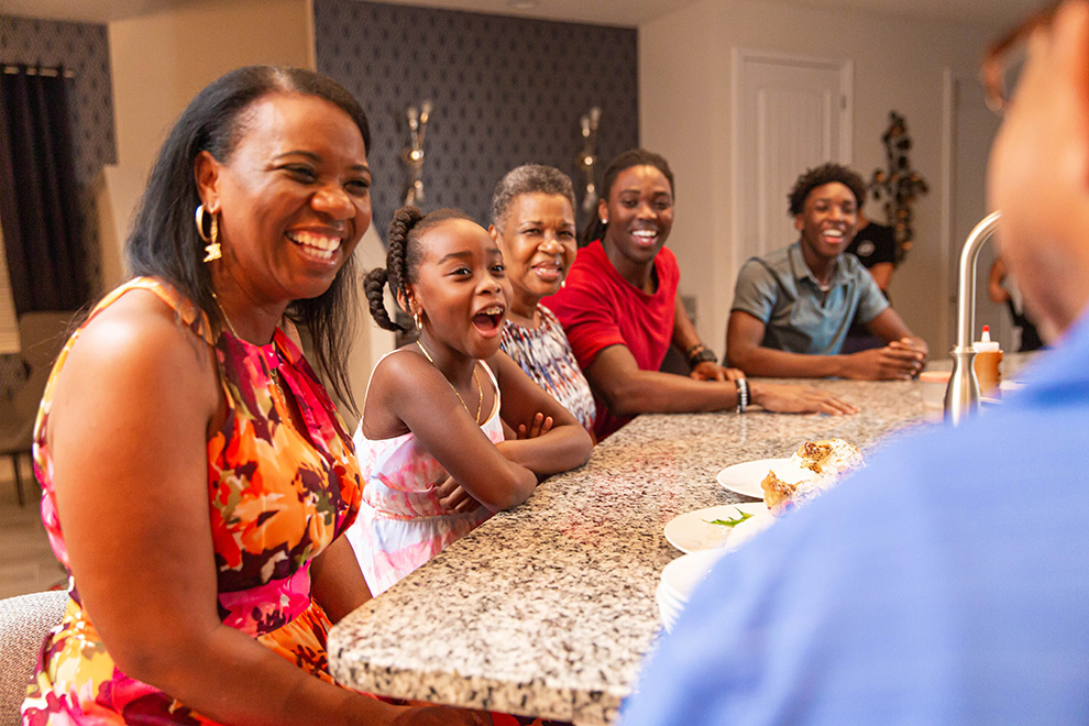 Multigenerational family watches an Encore Resort expert chef during an in-home chef experience at their vacation home.