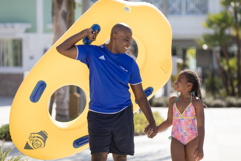 Young girl with her dad carrying a double tube to ride the Encore Resort water park slides.