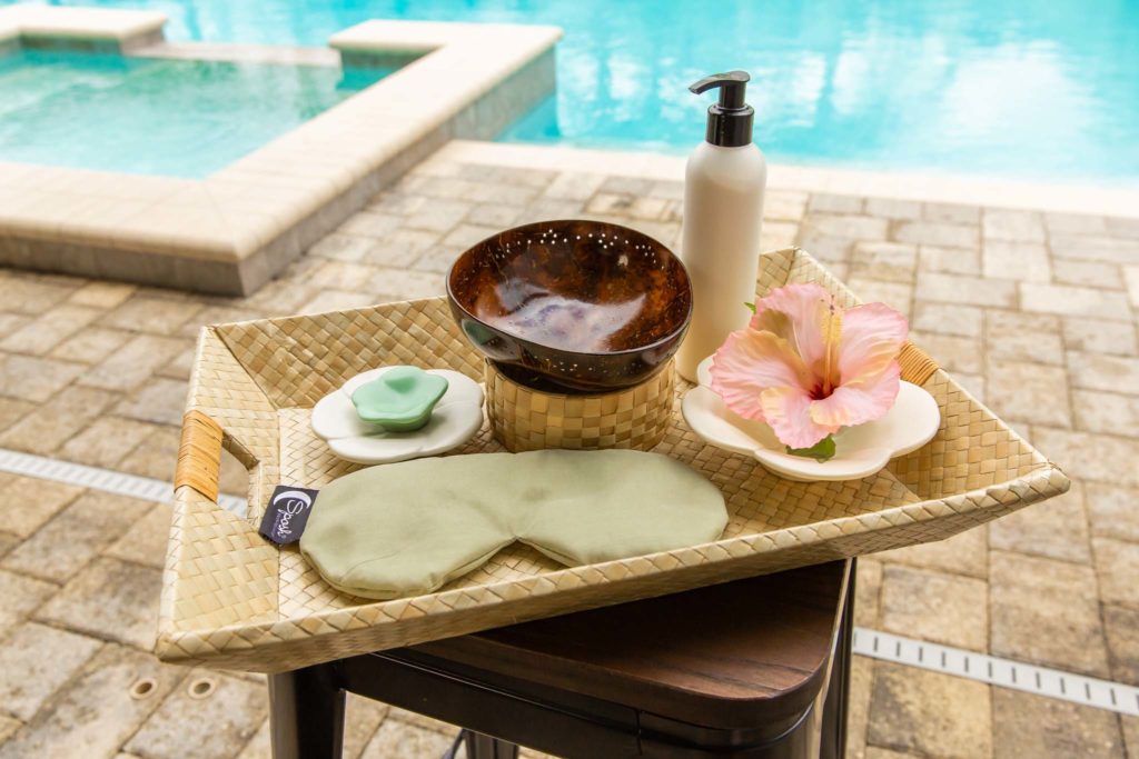 Spa scrub, face mask, and supplies on a table next to a private pool at an Encore Resort residence.
