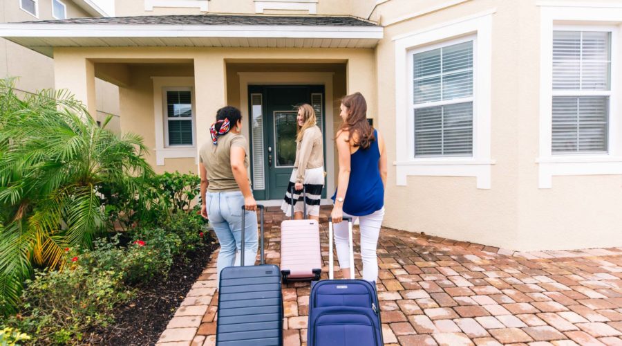 Three women happily arrive with luggage at their Encore Resort curated resort residence for a girls’ getaway trip.