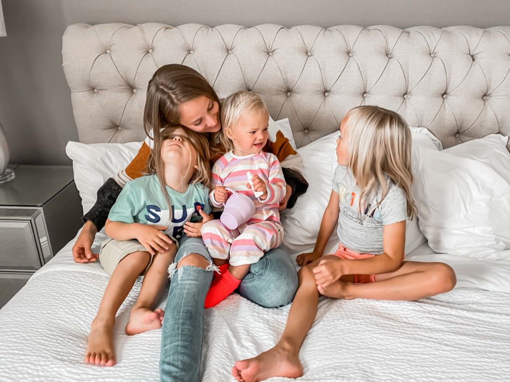 Mother and 3 kids sitting on a large king bed inside an Encore Resort at Reunion resort residence.