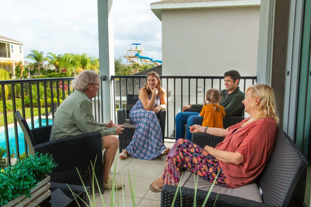Multigenerational family sitting on a covered balcony on a summer day at an Encore Resort at Reunion residence.