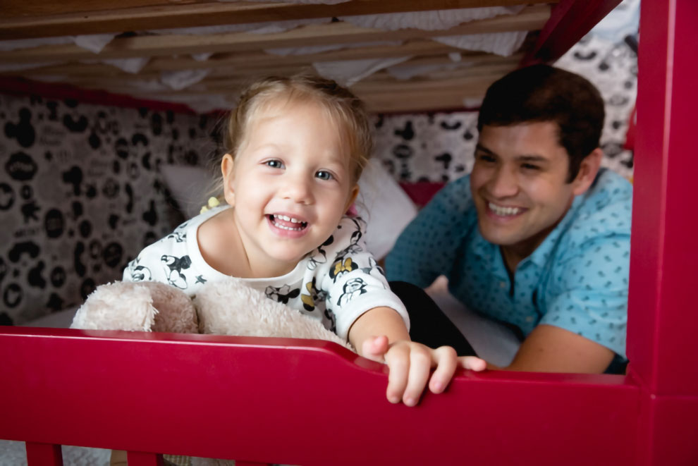 Smiling father and young child playing on the bottom bunk of a bunkbed set in an Encore Resort residence.