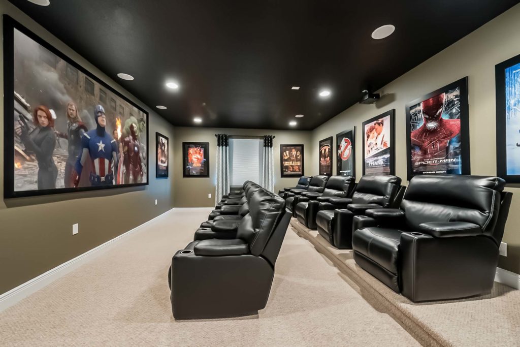 Private movie theater room in an Encore Resort residence with a large, wall-mounted screen, two rows of comfortable leather seats, and movie posters on the walls.