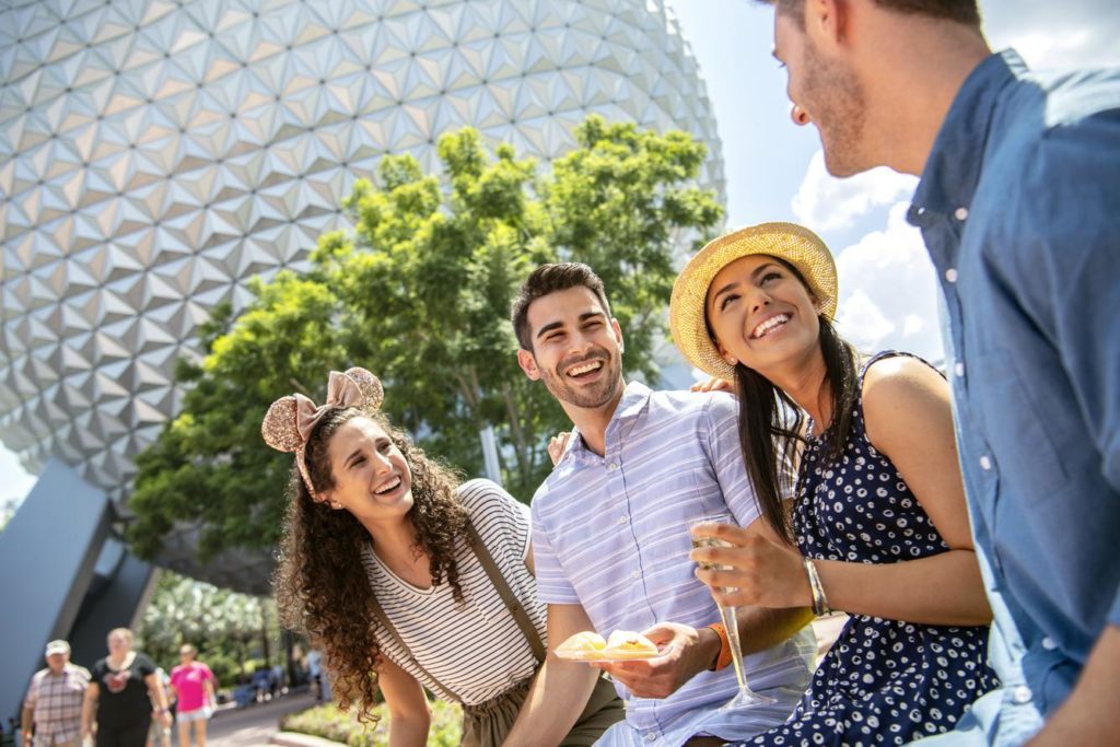 Two couples sharing food and wine at Epcot theme park at Walt Disney World.