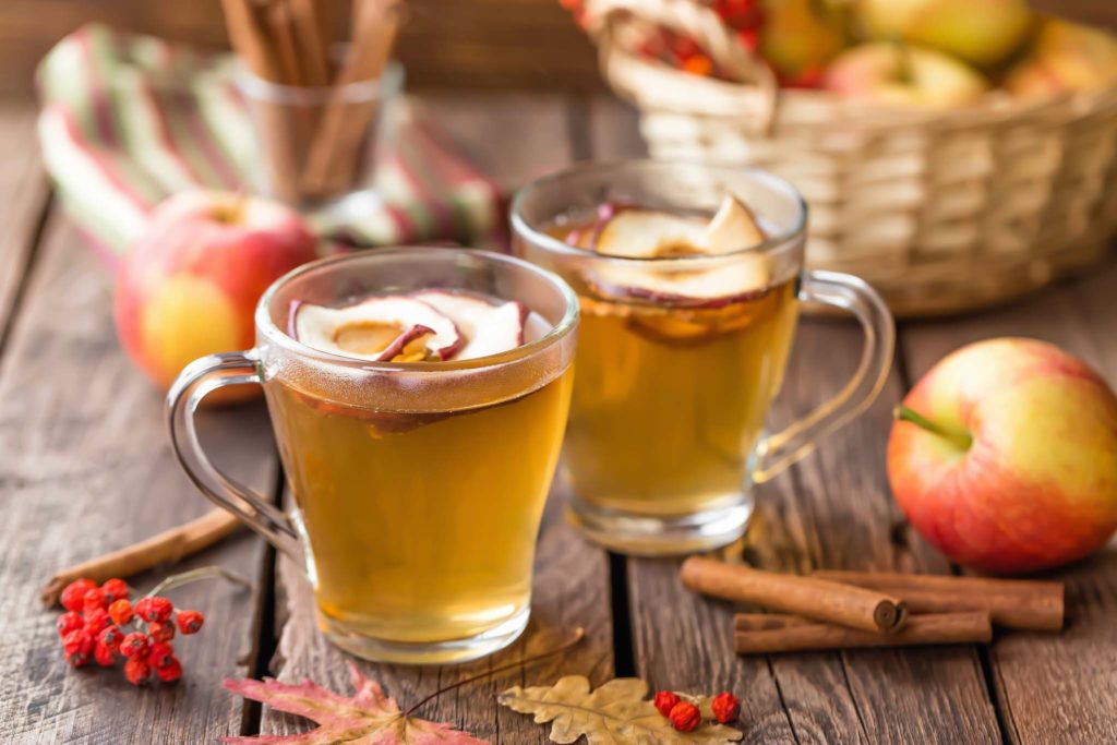 Apple cider glasses garnished with apple slices and cinnamon.