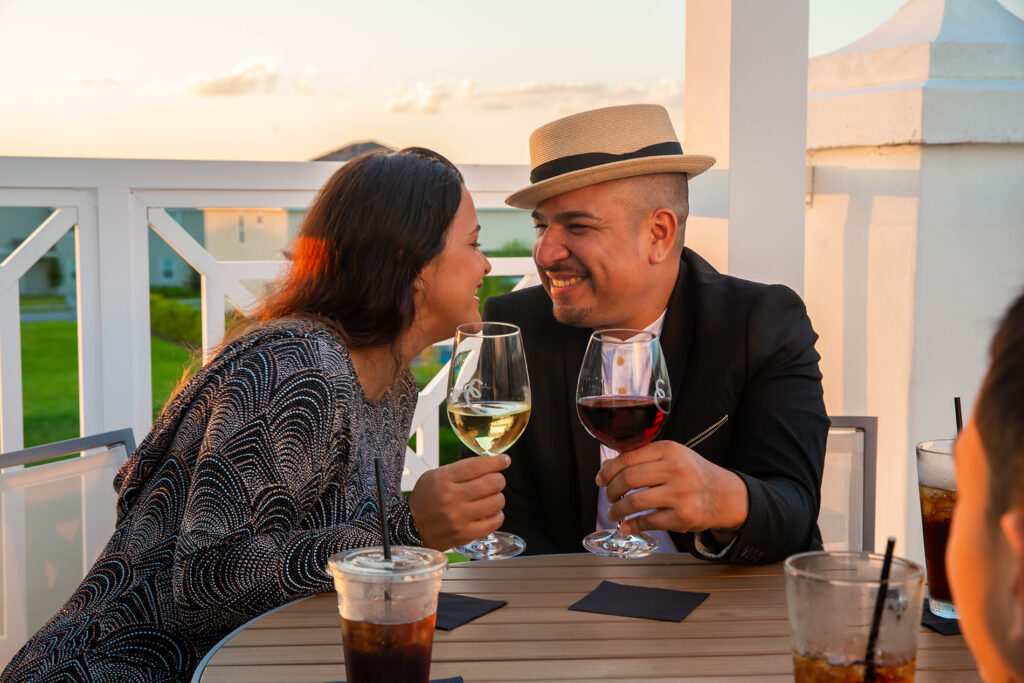Couple toasting glasses of wine on a balcony at sunset