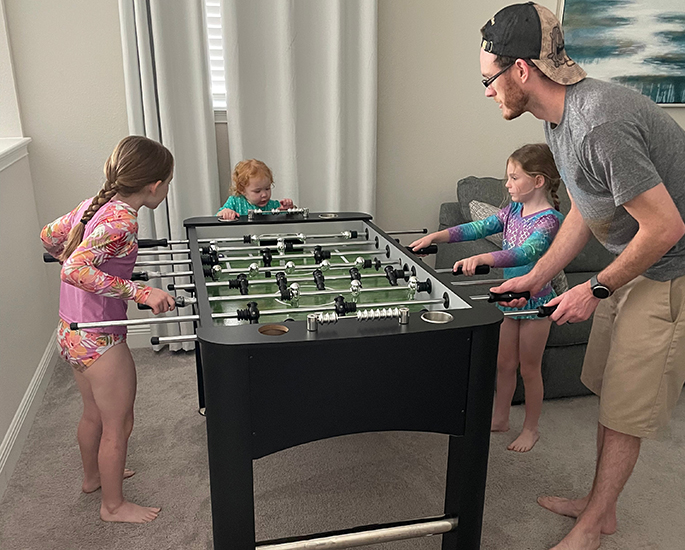 Father and daughters enjoying a game of foosball