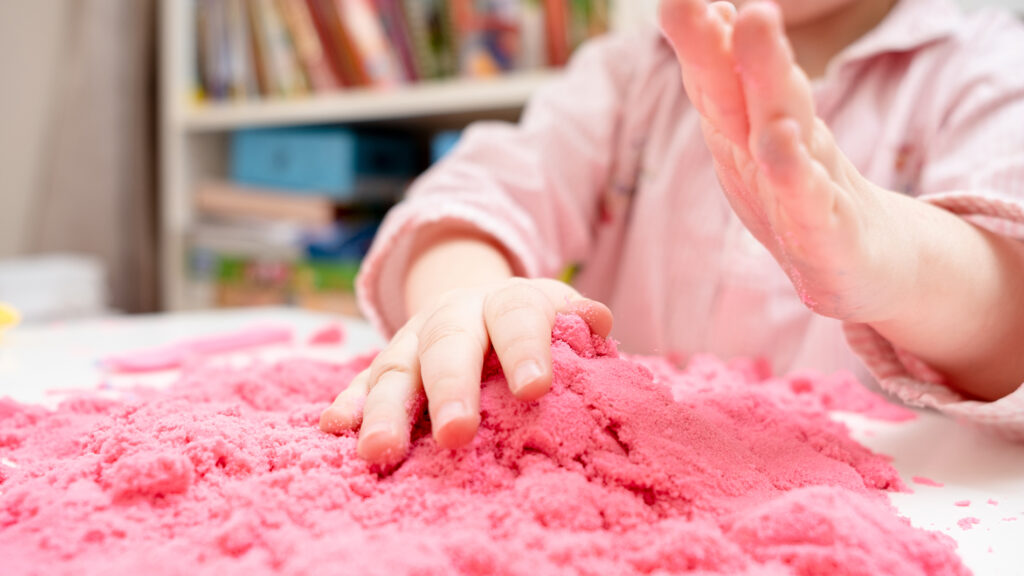 Child playing with pink sand