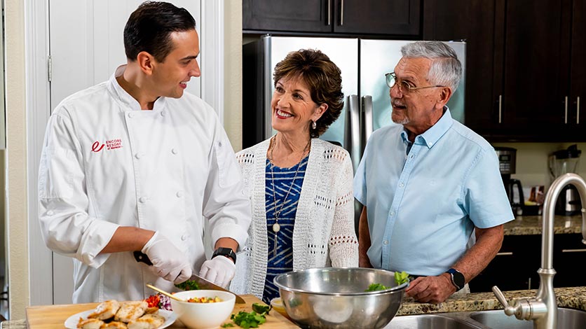 Older couple speaking with private chef preparing their meal