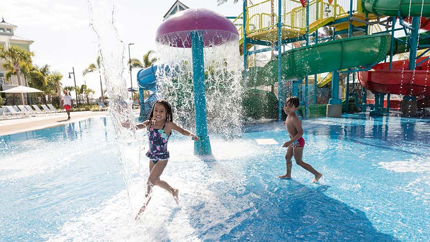 Kids having fun under a mushroom spray fountain in the pool at the Encore Resort Water Park