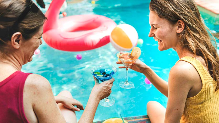 Woman having cocktails at the edge of a pool