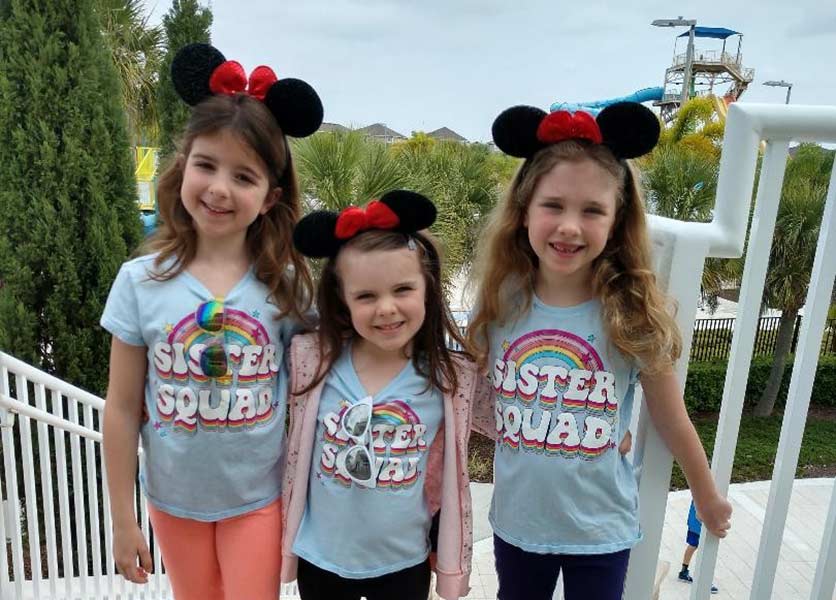 Three little girls in matching t-shirts wearing Minnie Mouse ears