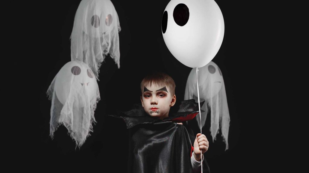 Young boy dressed as a vampire holding a balloon