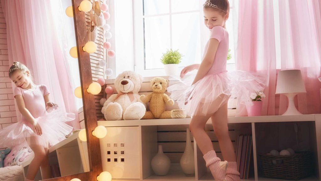 Girl dressed as ballerina posing in front of a mirror