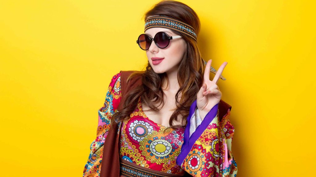 Woman in a hippie costume making a peace sign